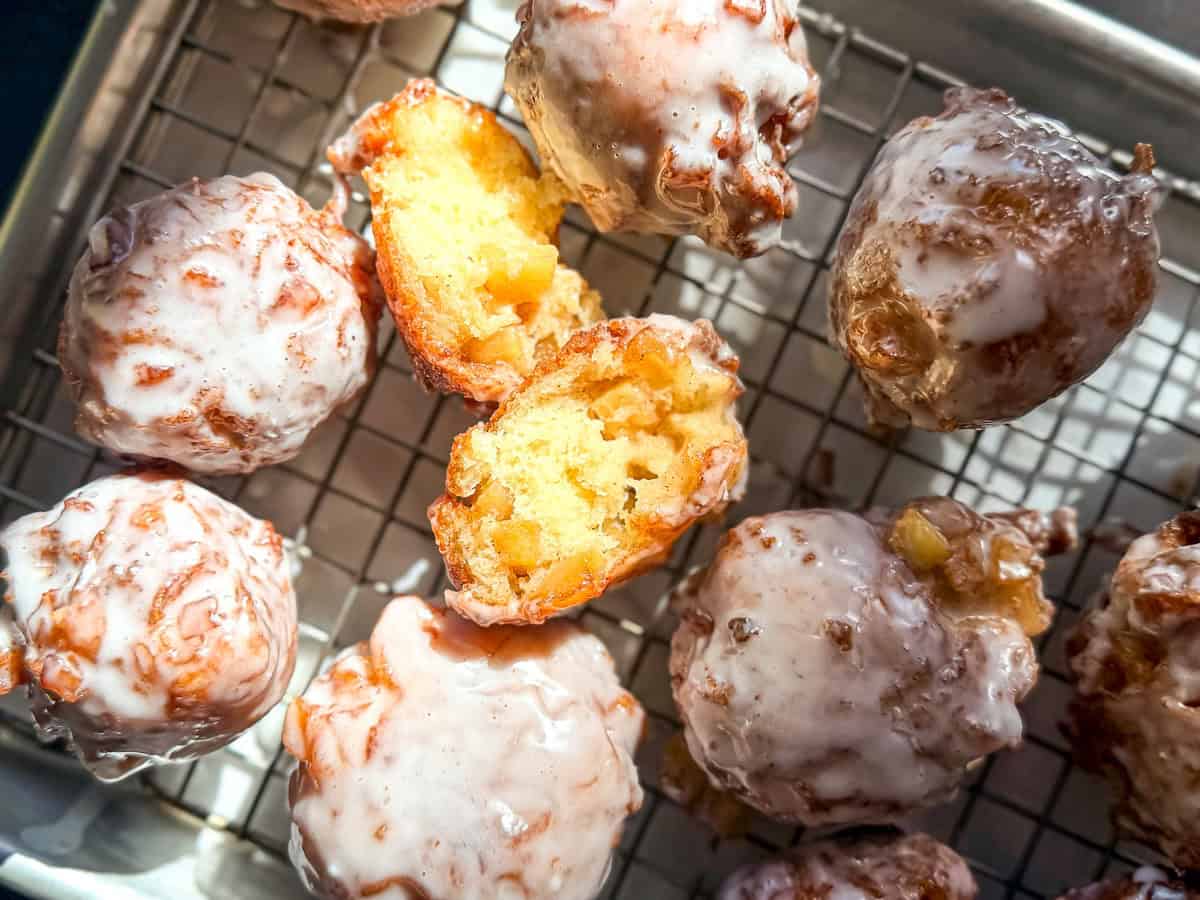 Overhead image of apple fritters with one opened to show the fluffy apple filled interior.