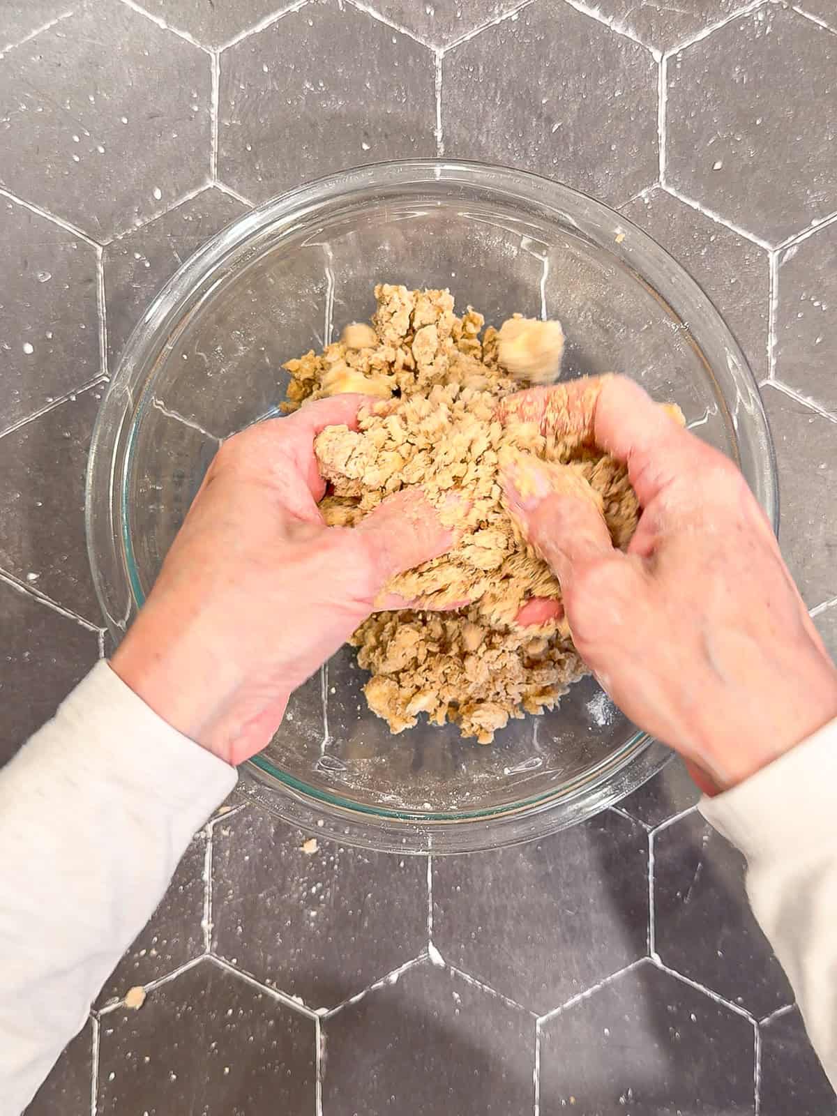 Using my hands to make streusel in a glass bowl.