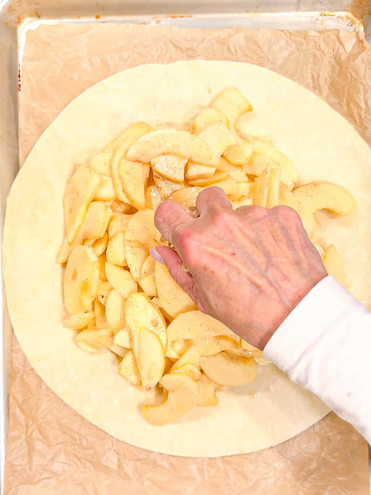 Placing apples in the center of a pie crust.