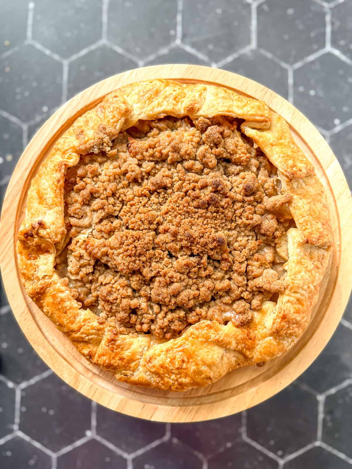 Apple streusel galette on a cake stand.