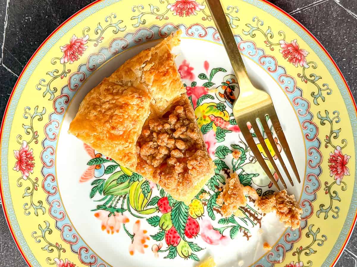 Slice of apple streusel galette on a yellow floral plate.