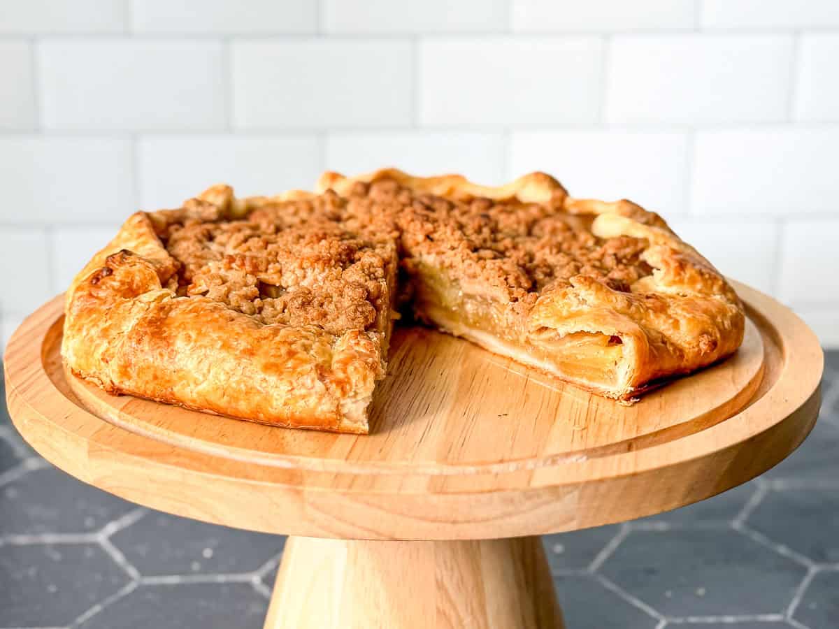 Side view of an apple streusel galette on a cake stand.