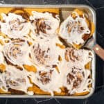 Sheet pan cinnamon roll pancake with a slice taken out.