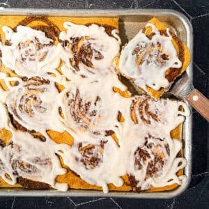 Sheet pan cinnamon roll pancake with a slice taken out.