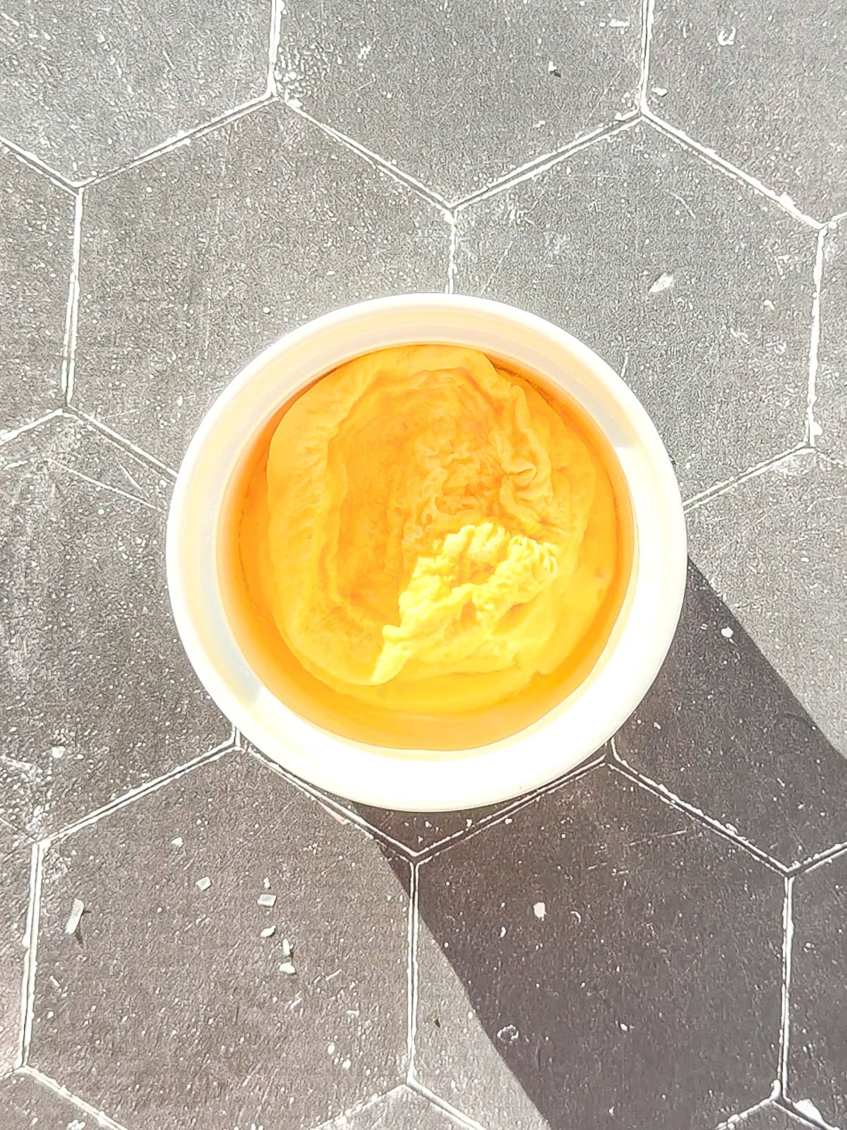 A cooked microwave omelette in the bottom of a white ramekin.
