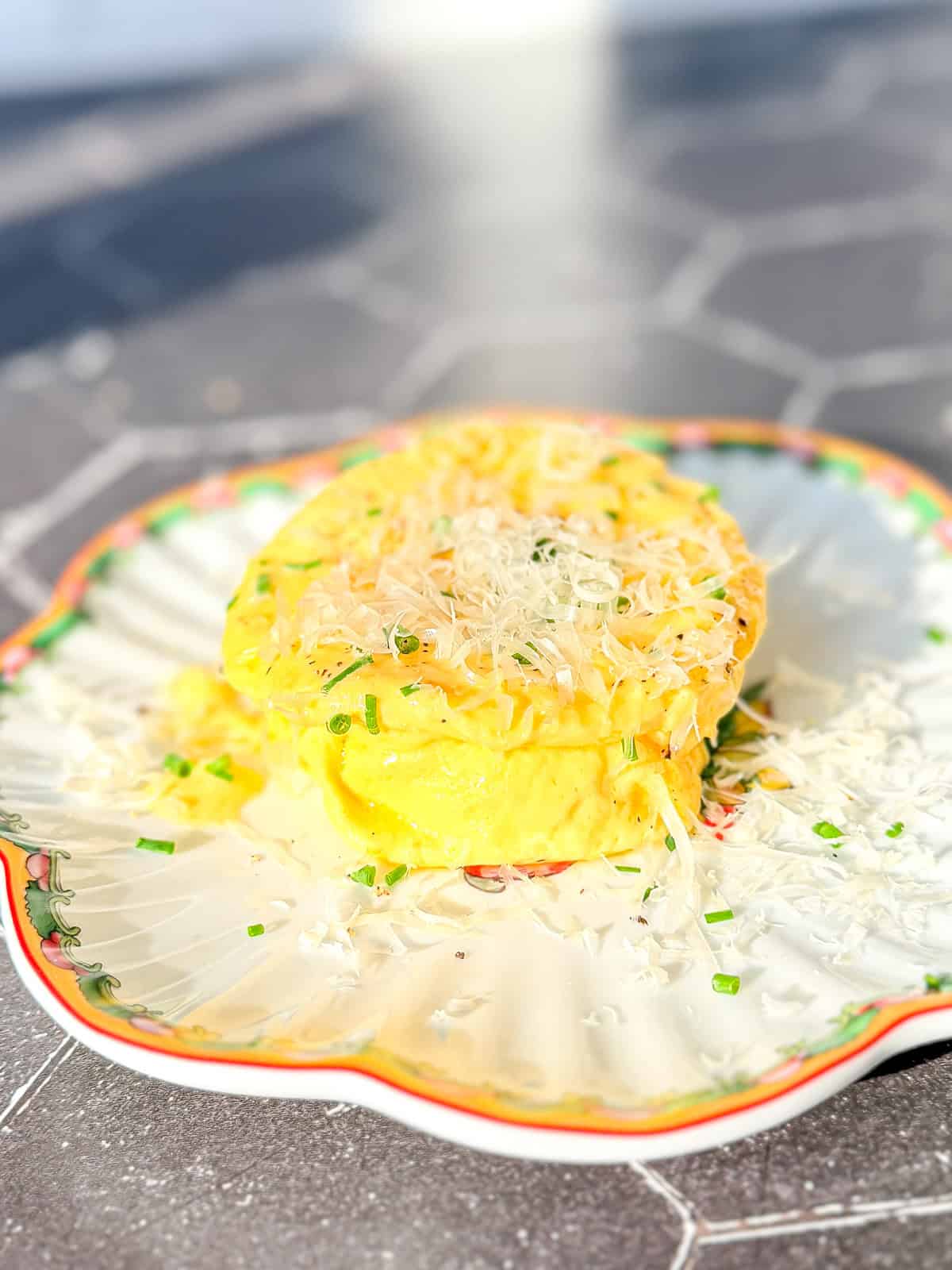 A microwave omelette with grated Parmesan and fresh chives on a scalloped plate.