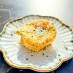A microwave omelette with grated Parmesan and fresh chives on a scalloped plate.