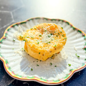 A microwave omelette with grated Parmesan and fresh chives on a scalloped plate.