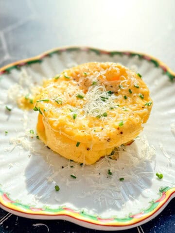 A microwave omelette with grated Parmesan and fresh chives on a scalloped plate.